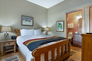 A bedroom with a wooden bed, two bedside tables with lamps, a nightstand, a wooden dresser, and a mirror.