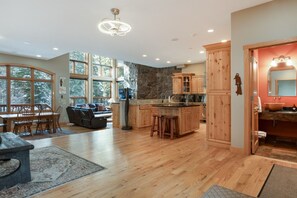 A spacious kitchen with wooden cabinets, a stone accent wall, and a large island. - Large East Vail Home - Steps to Bus & Gore Creek (Vail)