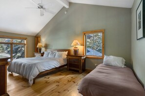 A bedroom with two beds, wooden flooring, a ceiling fan, and a window with a view of snow-covered trees. - Large East Vail Home - Steps to Bus & Gore Creek (Vail)