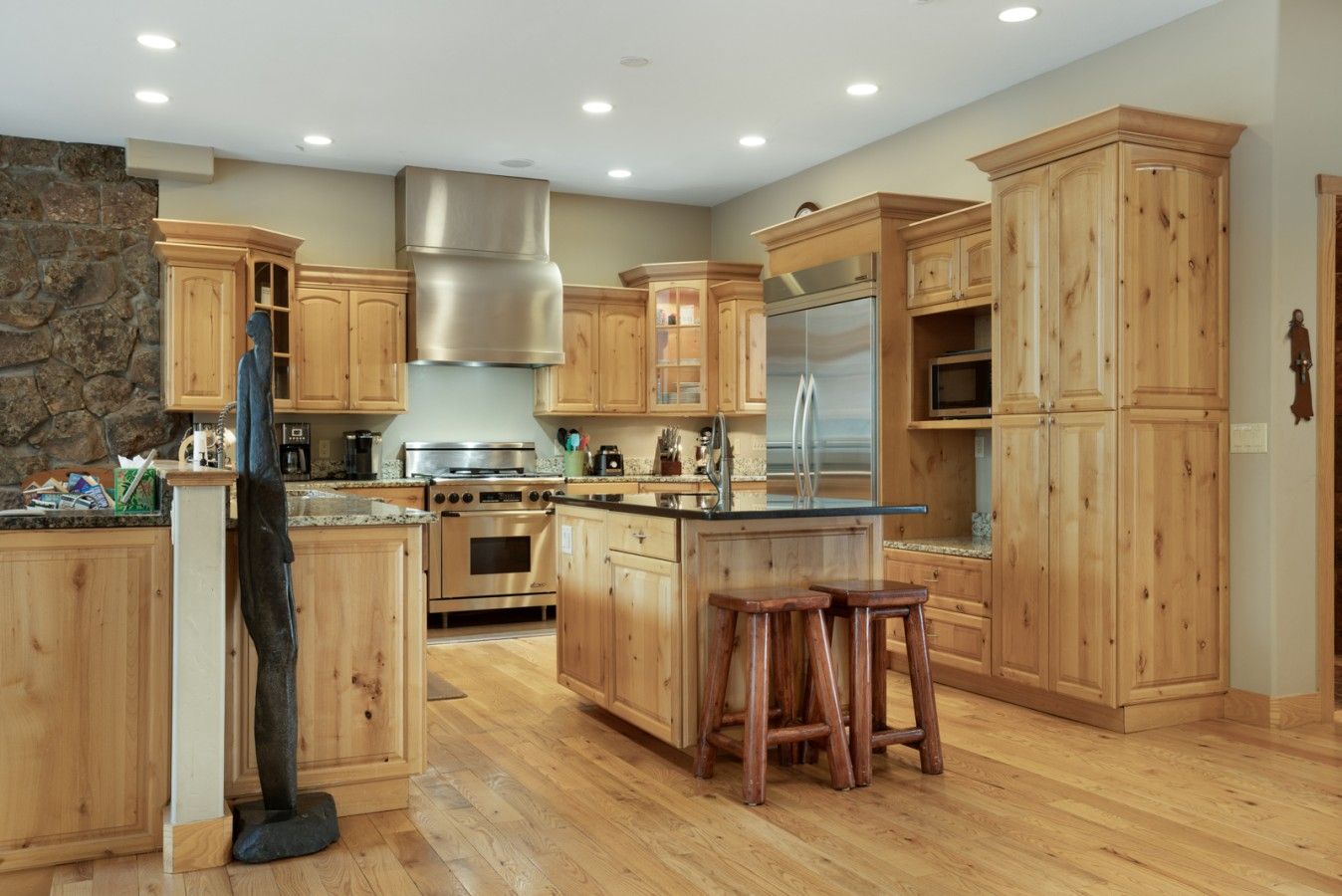 A spacious kitchen with wooden cabinets, a stainless steel range hood, a double oven, and a refrigerator.