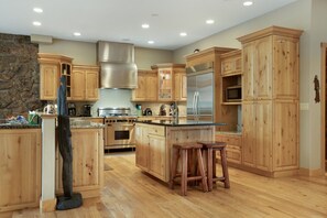 A spacious kitchen with wooden cabinets, a stainless steel range hood, a double oven, and a refrigerator. - Large East Vail Home - Steps to Bus & Gore Creek (Vail)