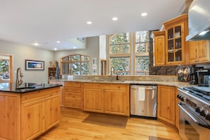 A kitchen with wooden cabinets, granite countertops, a stainless steel dishwasher, and a stove.