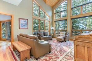 A spacious living room with large windows, a piano, and a fireplace.