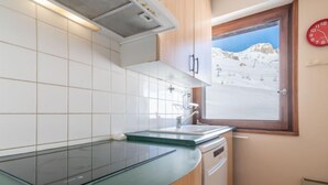 Una cocina moderna con horno empotrado, ventana con vistas a un paisaje nevado y un reloj rojo en la pared.