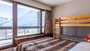 Una habitación con literas, un ventanal con vistas a la montaña y una escalera de madera.