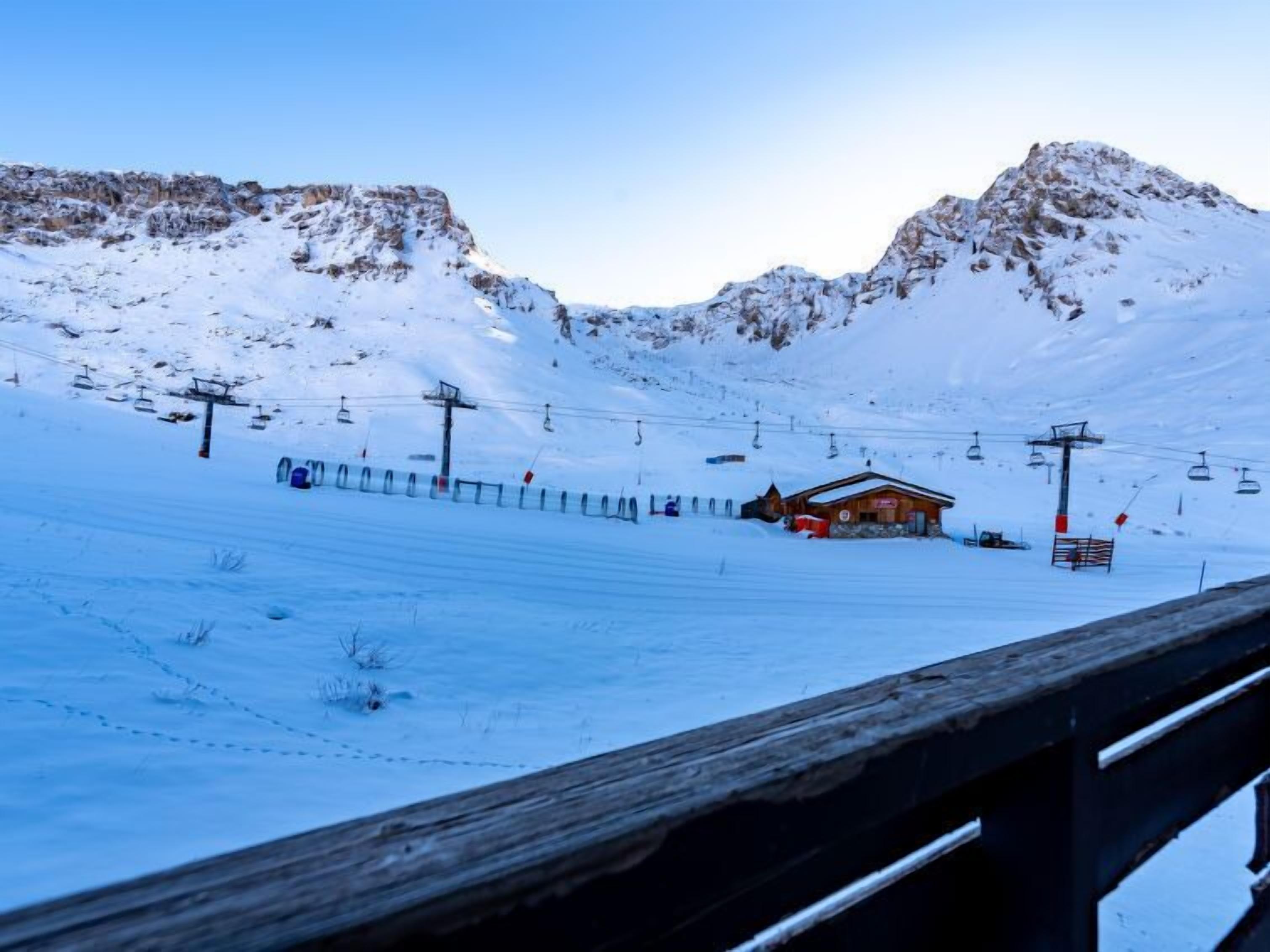 A snow-covered mountain landscape with a wooden cabin and ski lift infrastructure.