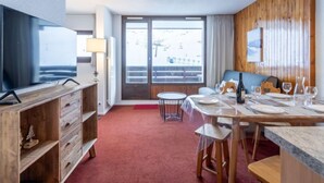 Ein modernes Hotelzimmer mit Essbereich, Fernseher, Holzvertäfelung und Blick ins Freie.