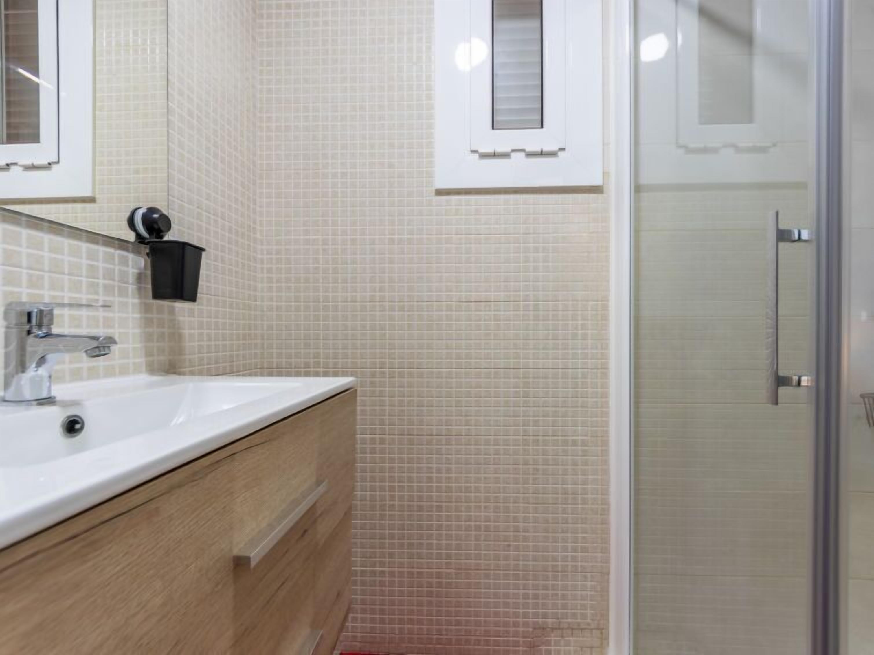 A bathroom with a sink, mirror, and a glass shower enclosure.