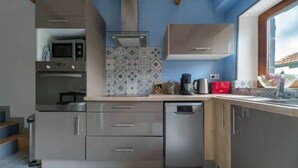 A modern kitchen with built-in appliances, a dishwasher, and a window providing natural light.