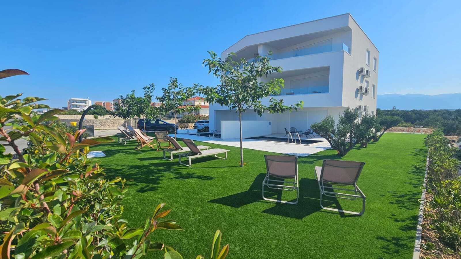 A modern building with a pool area, outdoor seating, and a well-maintained lawn.