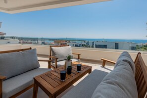 Een balkon met een houten tafel, twee banken en een bloempot.
