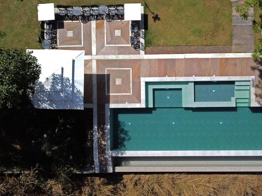 An aerial view of a property with a swimming pool, outdoor seating area, and a landscaped garden.