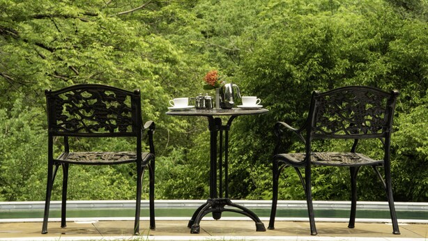 Een tafel met twee stoelen en uitzicht op een waterval en weelderige begroeiing.