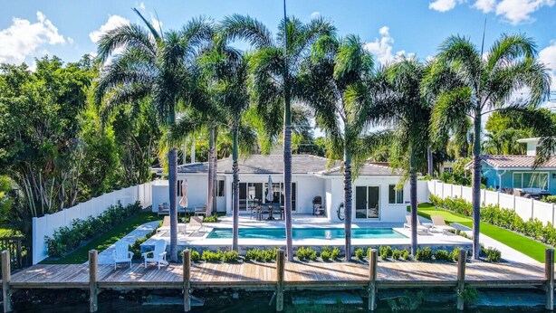 A waterfront property with a pool, palm trees, and a dock. - Lakefront Family Fun Home with Private Dock 3BR 2B (Fort Lauderdale)