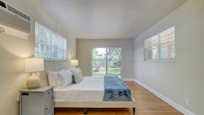 A bedroom with a bed, bedside tables, and a view of the outdoors. - Tranquil Poolside Bliss + Pergola Deck & Turf Yard (Fort Lauderdale)