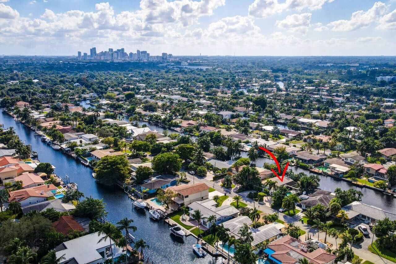 Une vue aérienne d’un quartier résidentiel traversé par une rivière, entouré de maisons et de verdure.
