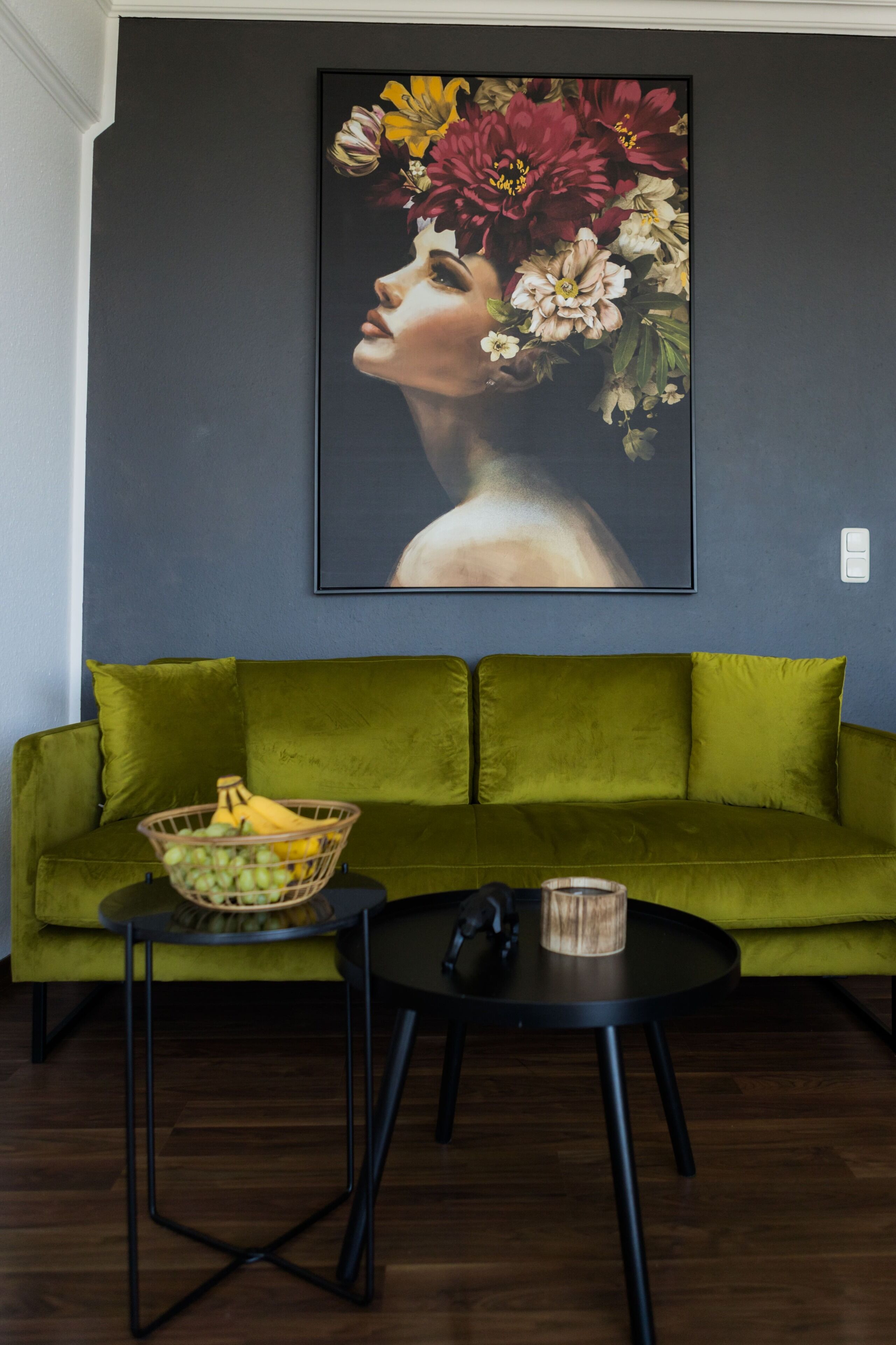 A green sofa with a fruit basket and a coffee cup on a small table.