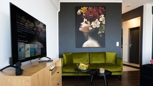 Una sala de estar moderna con un sofá verde, un aparador de madera, un televisor de pantalla plana y un cuadro en la pared.