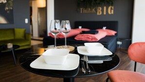 Un comedor moderno con una mesa de mármol negro, platos blancos y dos copas de vino.