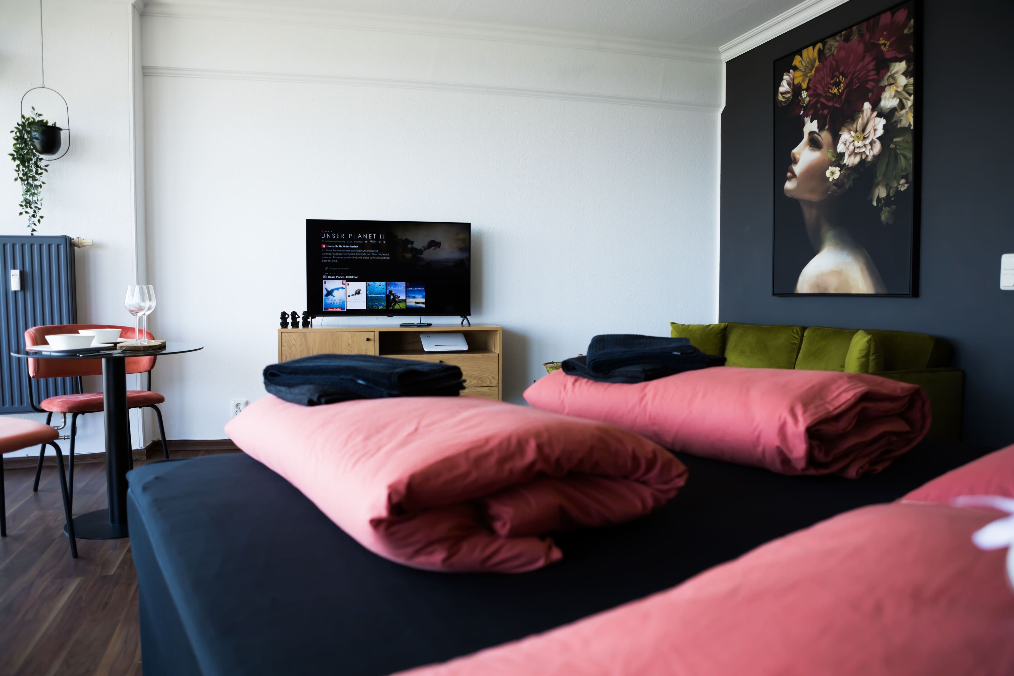 A modern hotel room with a bed, a desk with a computer, a chair, and a TV on a stand.