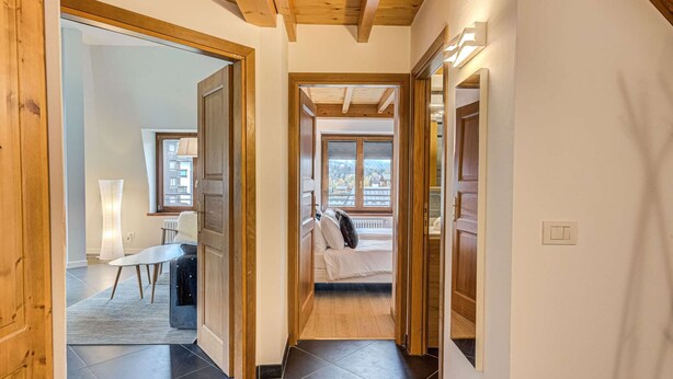 A hallway leading to a bedroom with a view of a cityscape.
