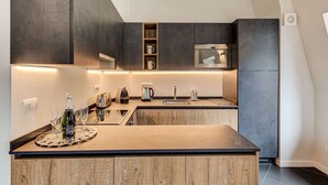 A modern kitchen with dark cabinetry, a central island, and built-in appliances.