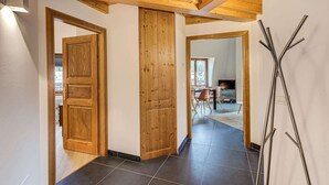 A hallway with wooden doors, a dining area with chairs and a table, and a modern metal sculpture.