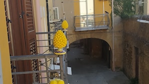 A narrow alleyway with a yellow building, a wooden door, and a metal railing. - Atena apartments 1 Agrigento center: your retreat in Agrigento (Agrigento)