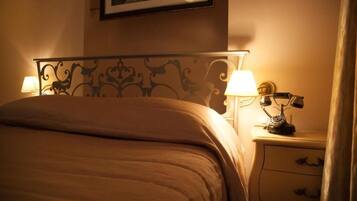 Habitación de hotel con cama, dos lámparas de noche, una mesita de noche con teléfono y un cuadro en la pared.