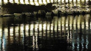 Une zone riveraine bordée de bâtiments, un quai avec des bateaux et un mur de pierre agrémenté de lampadaires.