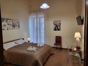 A hotel room with a bed, a chair, a TV, and artwork on the walls. - Atena apartments 2 Agrigento center (Agrigento)