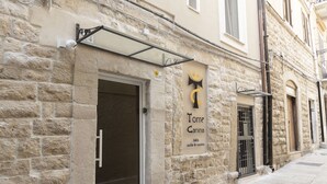 A stone building with a sign for "Torre Canina" indicating a b&b with 8 rooms. - Torre Canina Suite & Rooms  (Trani)
