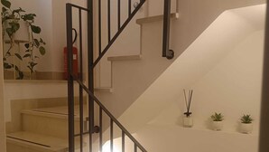 A staircase with a black railing, white walls, and potted plants on the landing. - Torre Canina Suite & Rooms  (Trani)