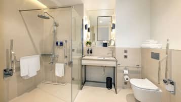 Un baño moderno con cabina de ducha de vidrio, tocador con espejo y retrete.