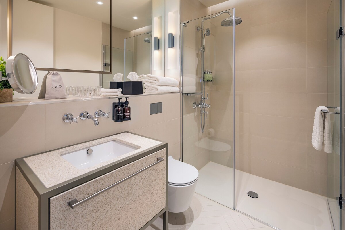 A modern bathroom with a glass shower enclosure, a sink with a mirror, and a toilet.