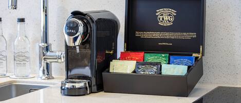 A kitchen counter with a coffee maker, a box of tea, and a bottle of water.