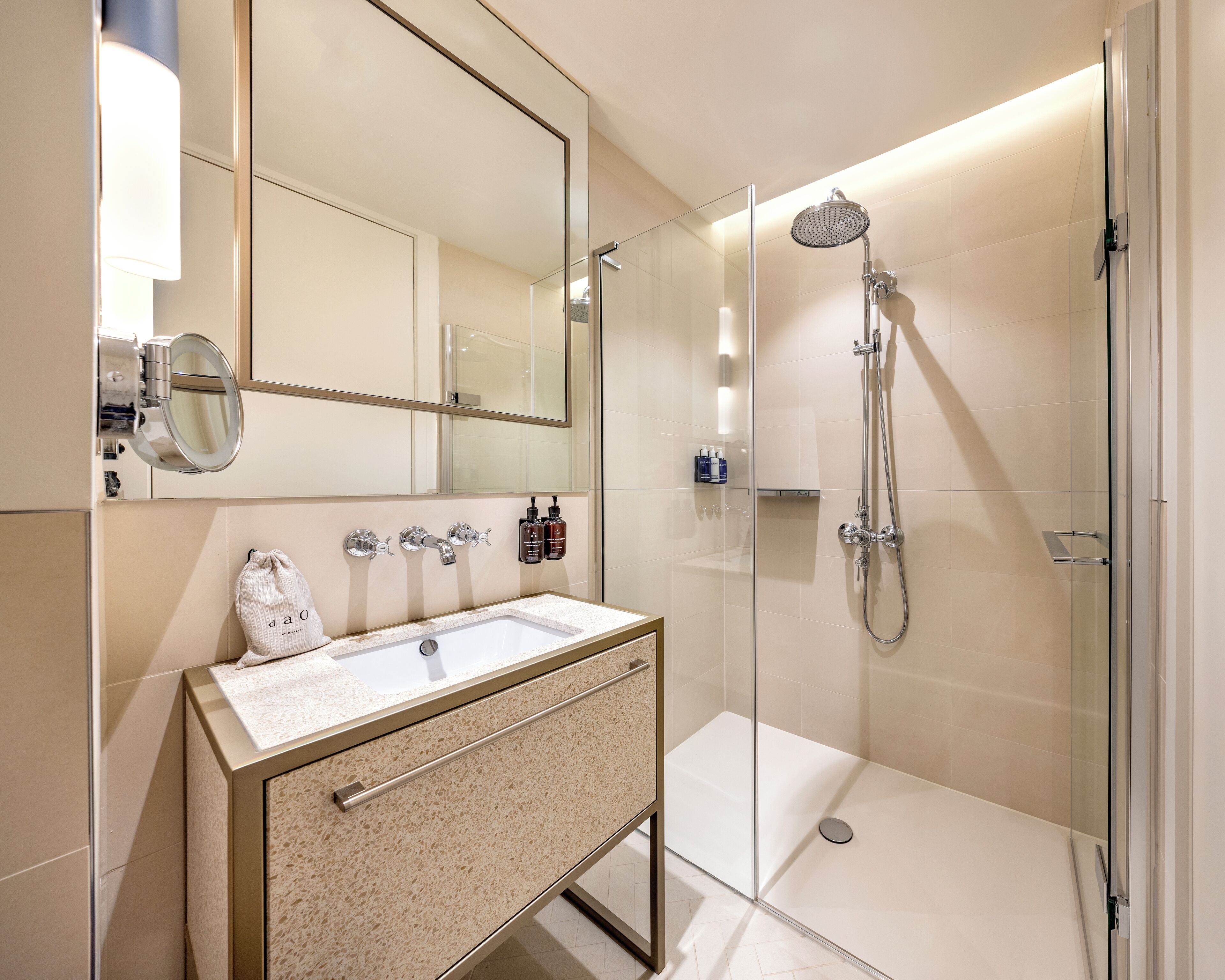 Un baño moderno con ducha de vidrio, un lavamanos con espejo y artículos de aseo en la pared.