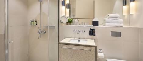 A modern bathroom with a glass-enclosed shower, a freestanding sink with a granite countertop, a large mirror, and a toilet.