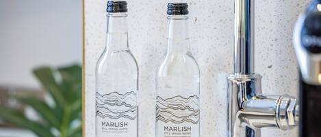 A kitchen sink with two glass bottles labeled "Marlish Still Spring Water" and a modern faucet.