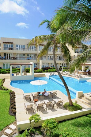 A hotel pool area with lounge chairs and a covered seating area. - The Phoenix Resort (San Pedro)