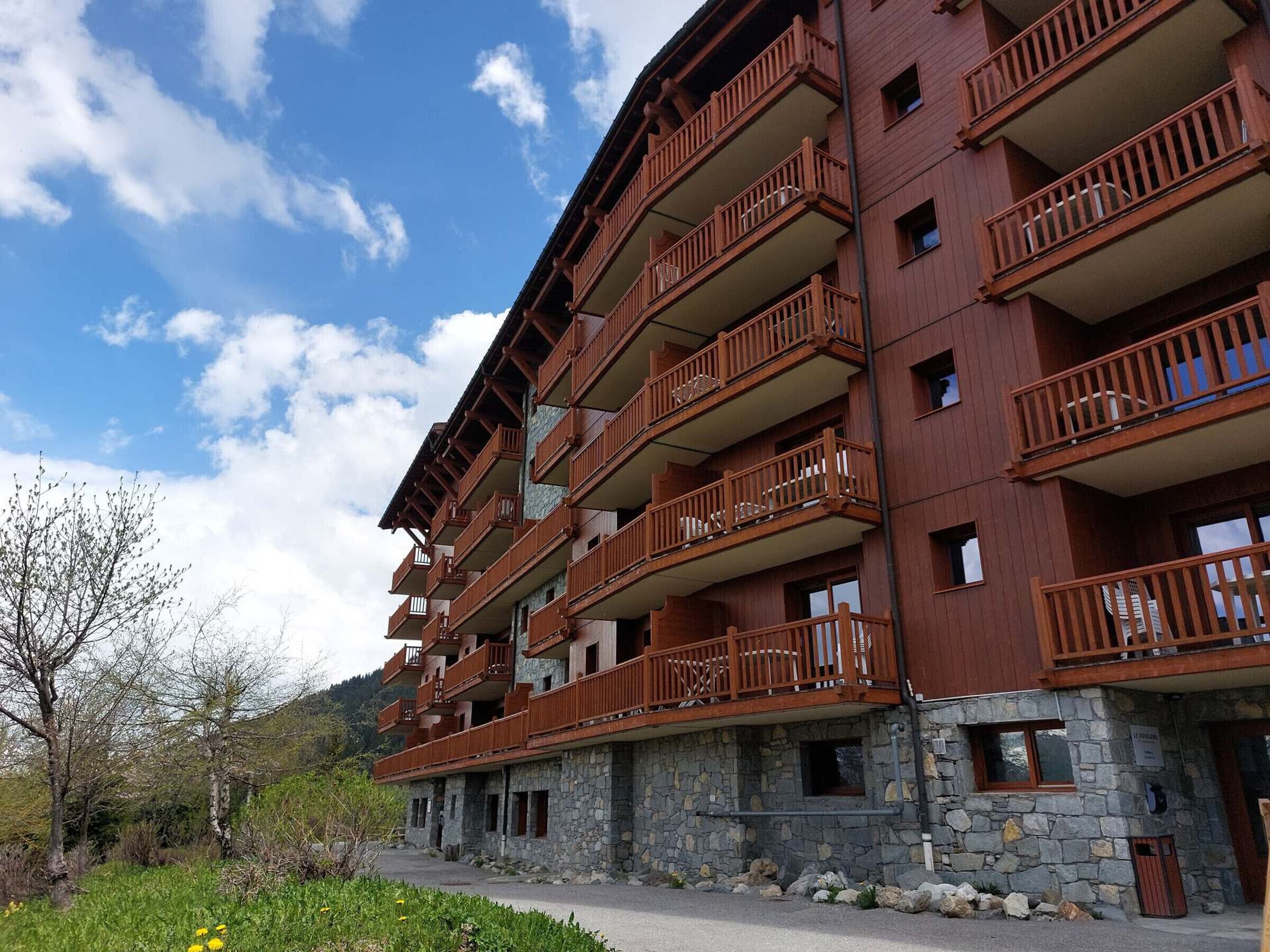 Ein mehrstöckiges Hotel mit hölzernen Balkonen und einer Stein-Fassade.
