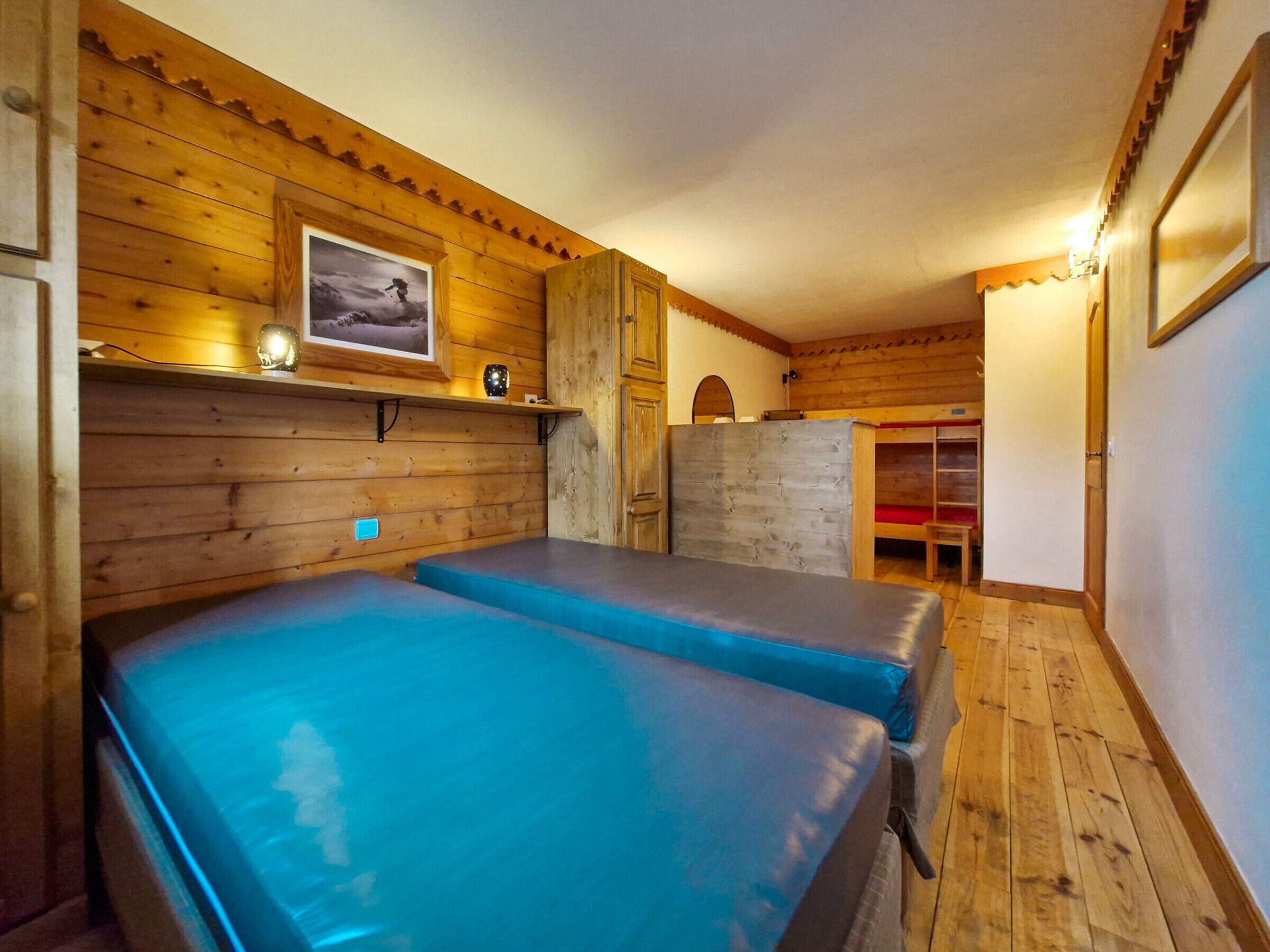 Una habitación con paredes de madera y una cama litera con ropa de cama azul.