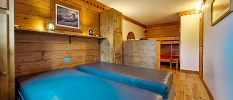 Una habitación con paredes de madera y una cama litera con ropa de cama azul.