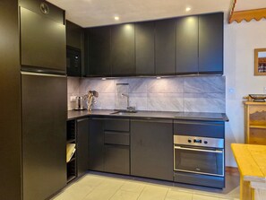 A modern kitchen with dark cabinetry, a stainless steel oven, and a built-in microwave.