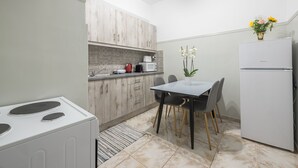 A compact kitchen with a dining area, a white refrigerator, a microwave, and a stove. - Athens Apartment 5-min to Metaxourgeio Metro  (Athina)
