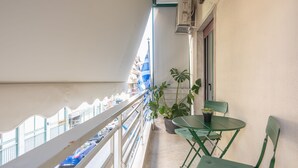 A balcony with a potted plant, a table, and chairs. - Athens Apartment 5-min to Metaxourgeio Metro  (Athina)