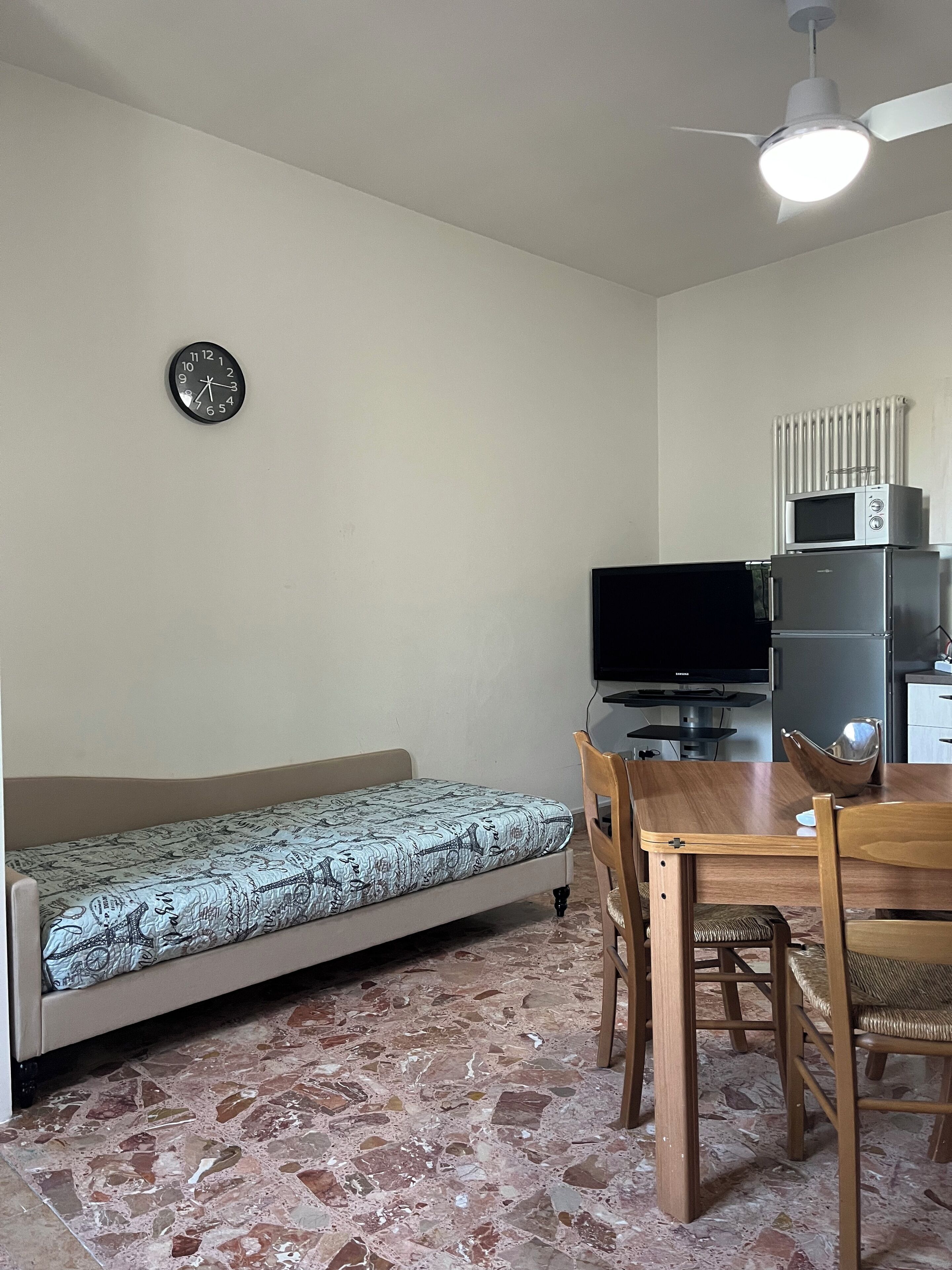 Un espacio habitable compacto con sofá, una mesa de comedor con sillas, televisor y microondas.