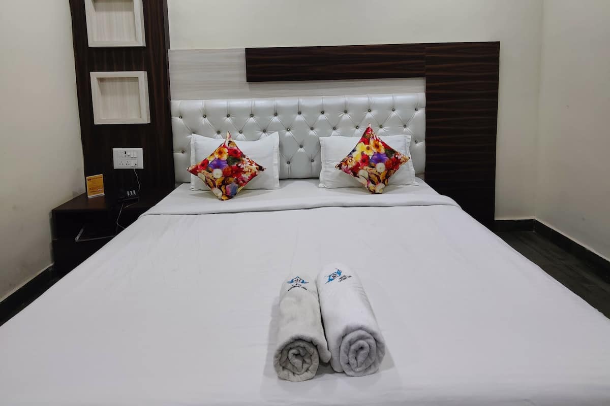 A neatly made bed with two rolled towels, a tufted headboard, and decorative pillows.