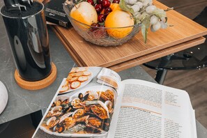 Una mesa con un bol de vidrio que contiene frutas y un libro abierto en una página de receta.