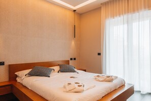 Een net opgemaakt bed met handdoeken, een houten hoofdbord en een nachtkastje met een lamp.